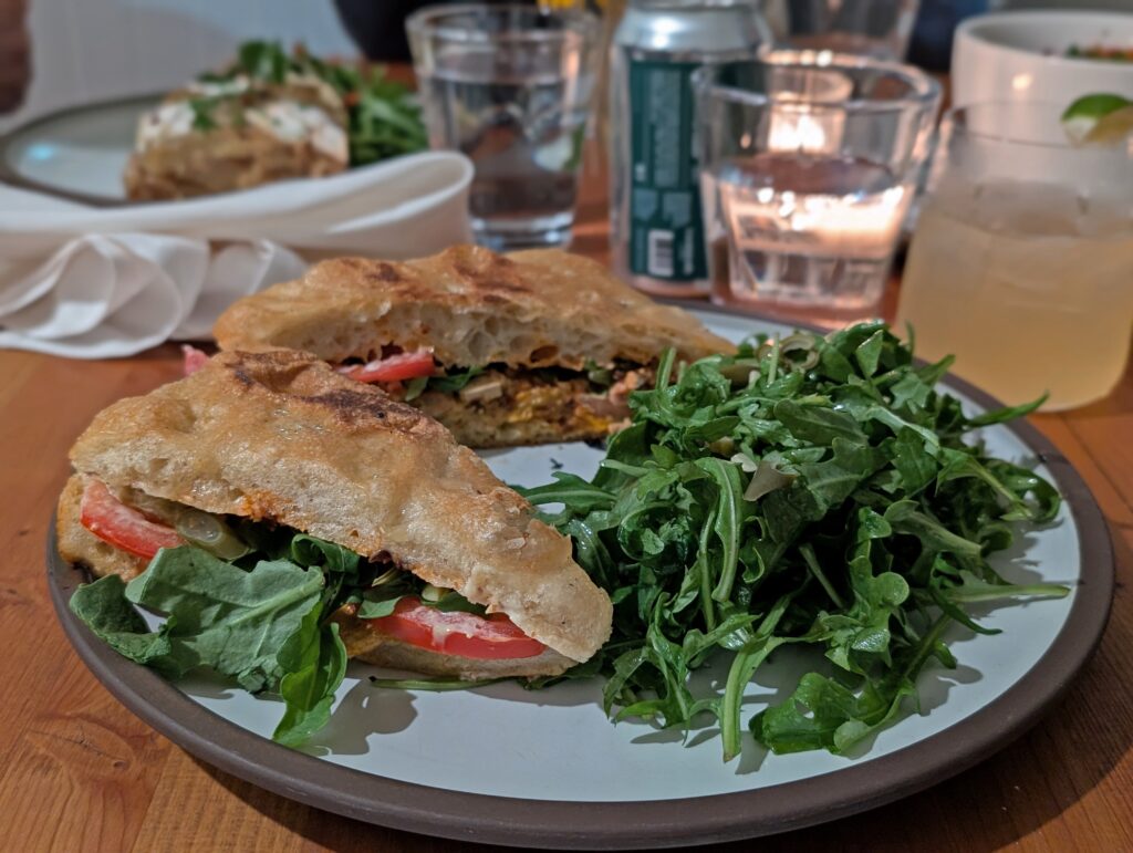 Close up of a veggie panini at 9 mile restaurant in Naramata, with multiple glasses in the background