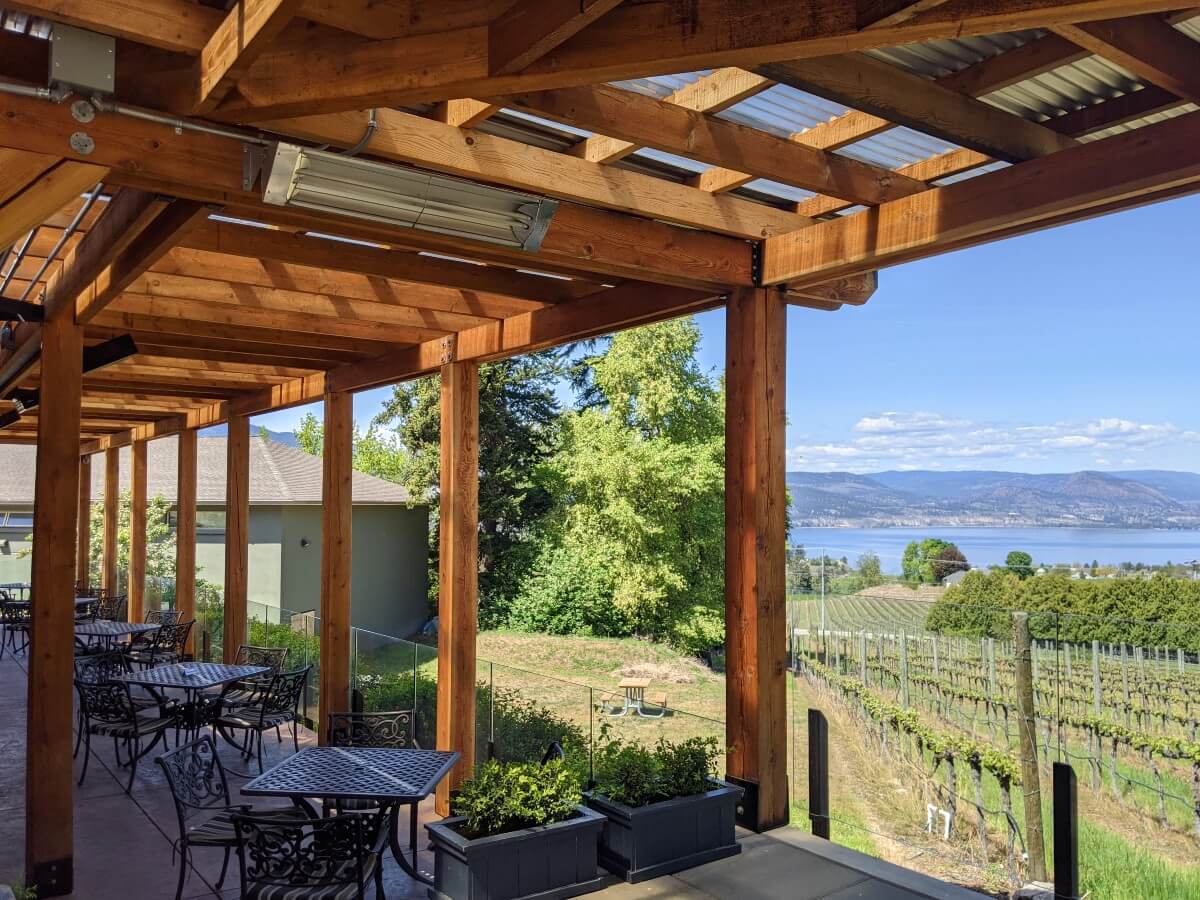 Side view of paved patio with seating and view of vineyards and Okanagan Lake