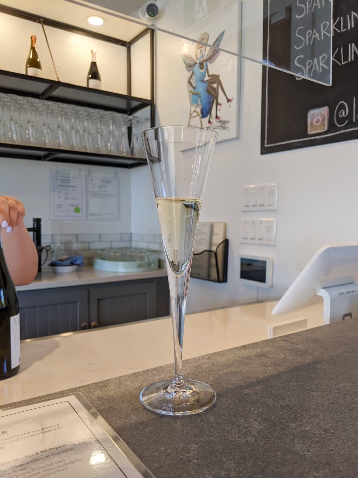 A champagne-style glass sits on a grey counter at La Petite Abeille