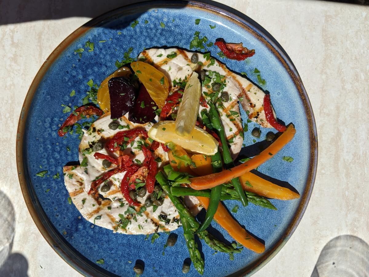 Overhead view of colourful dish on blue plate at Patio Restaurant at Lake Breeze, with carrots, asparagus, lemon, beetrot and sauce