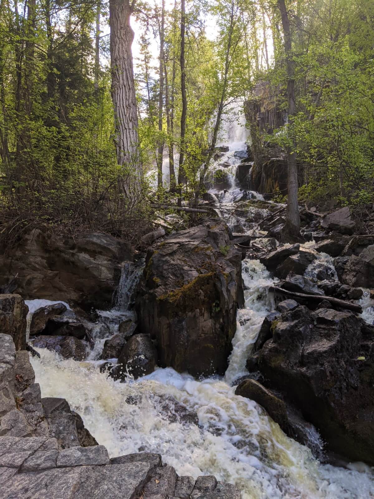 Looking up at large waterfall, with multiple cascades over rocks