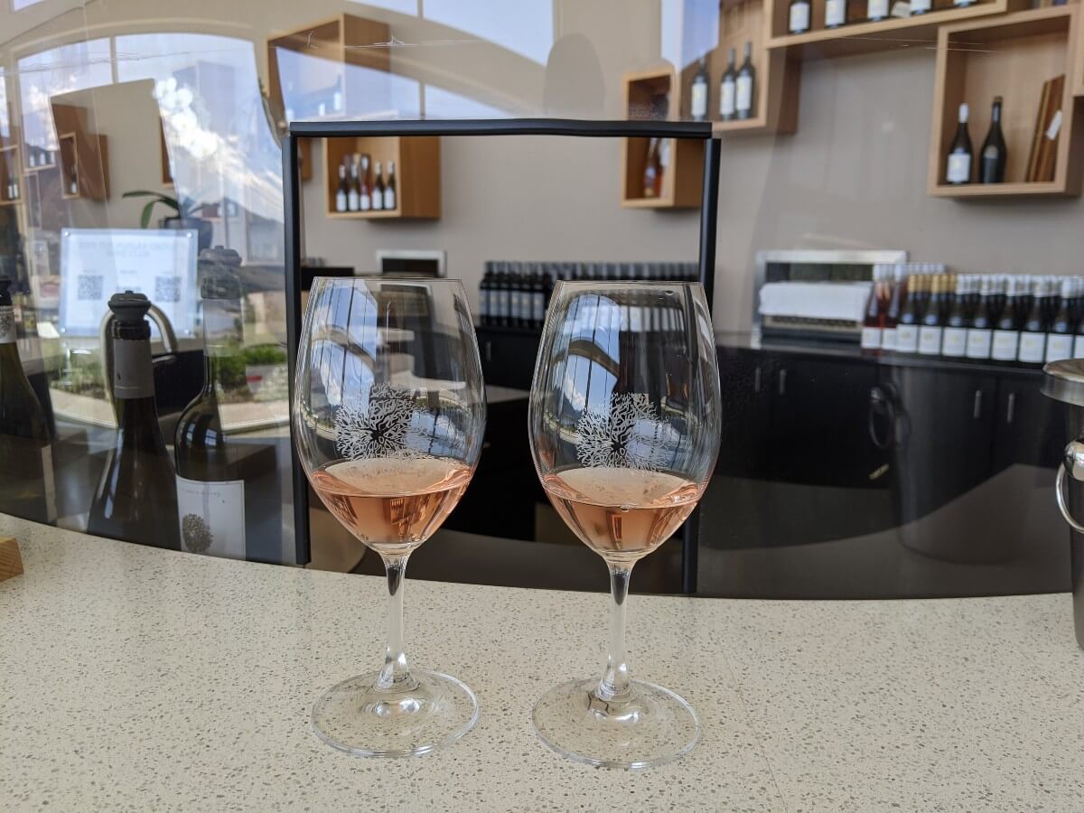 Two glasses of wine in Poplar Grove glasses, set onto tasting bar. The glasses are partially filled with pink rosé wine