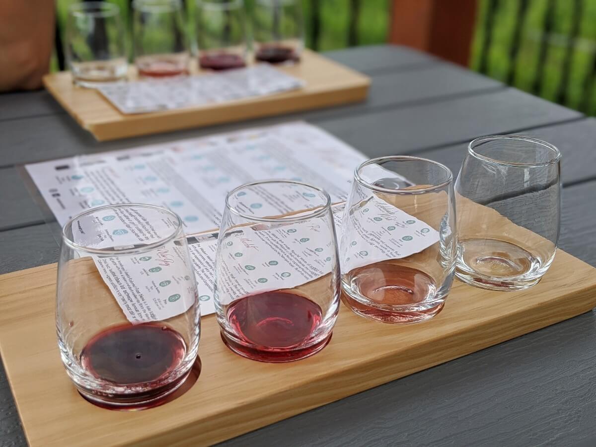 Close up of four stemless wine glasses on tasting flight, each with a small amount of wine in the glass