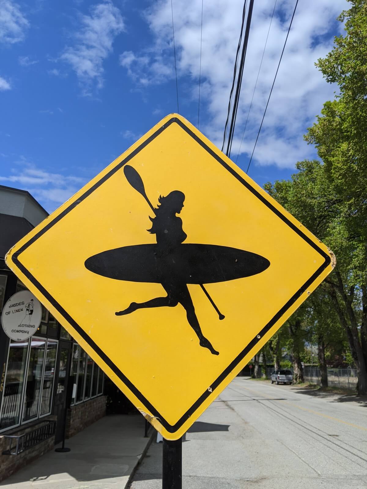 Close up of diamond shaped paddling sign with silhouette of woman with stand up paddle board and paddle