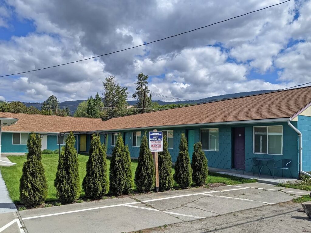 Naramata Courtyard Suites from the parking area, with blue painted motel style building