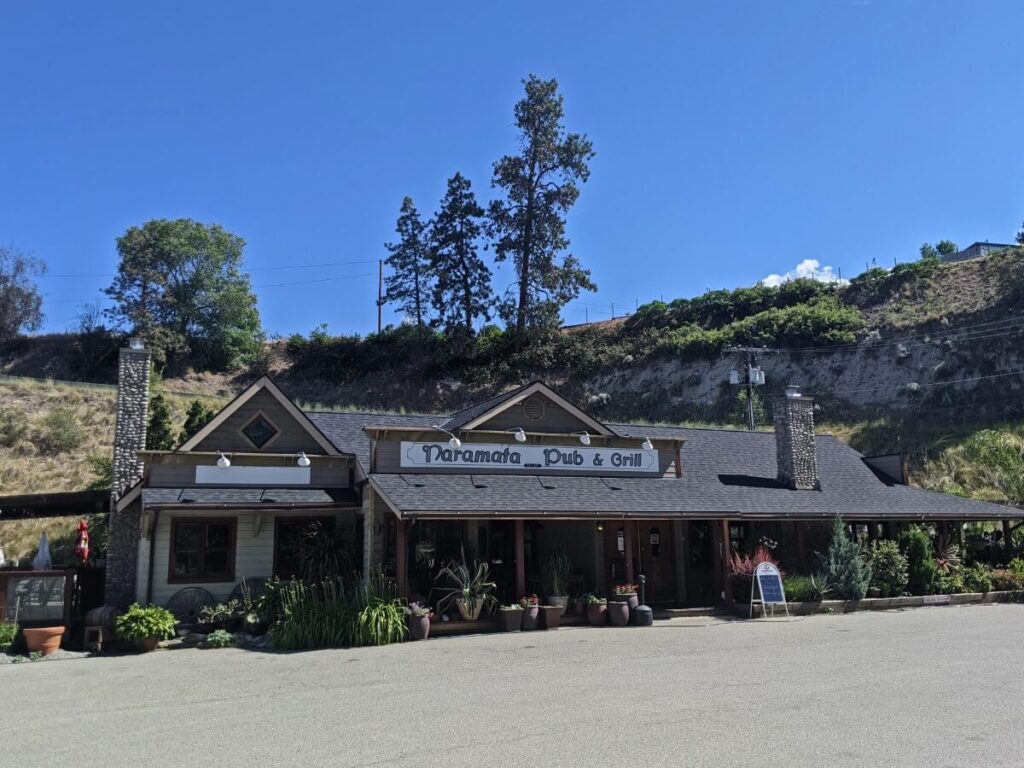 Exterior of Naramata Pub and Grill with single stroey building in front of bluff