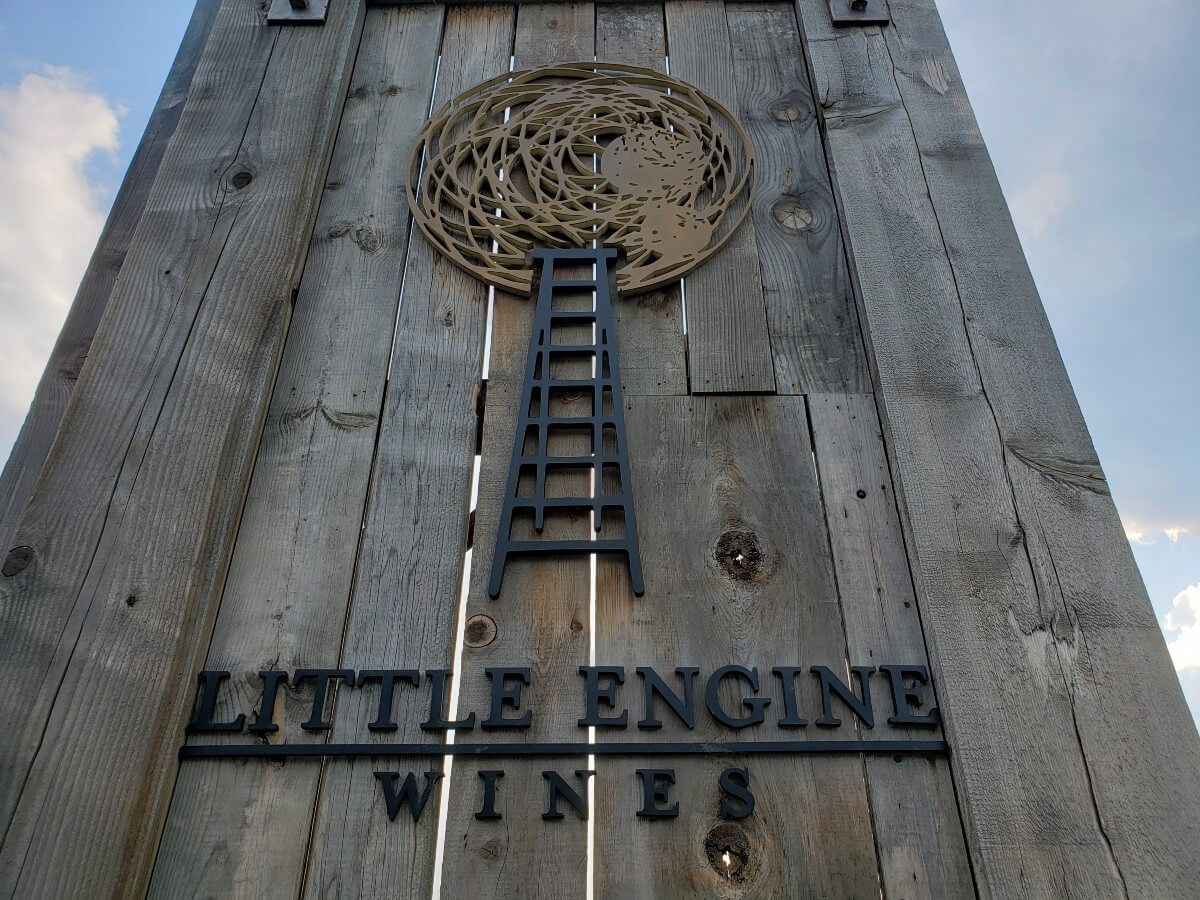 Close up of Little Engine Wines sign with vertical wooden slates, ladder and circle motif and winery name
