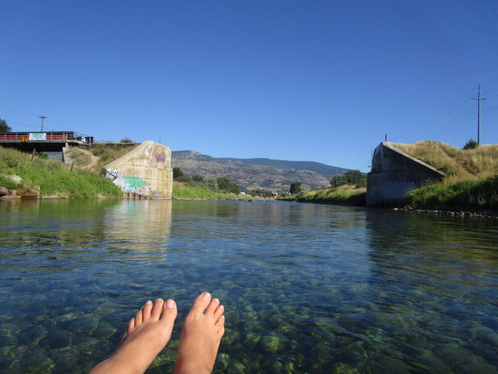 Feet view of clear water and blue skies while floating the Penticton Channel