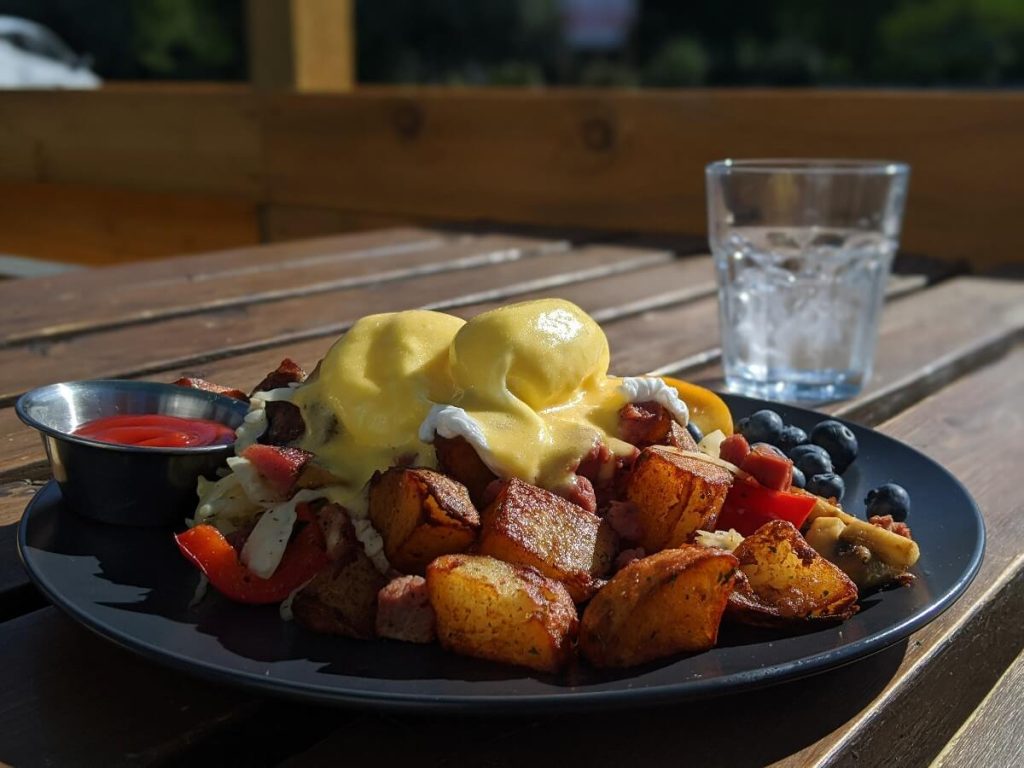 Close up of eggs benedict at Loki's Garage, with perfectly cooked eggs covered in hollandaise on top of potatoes