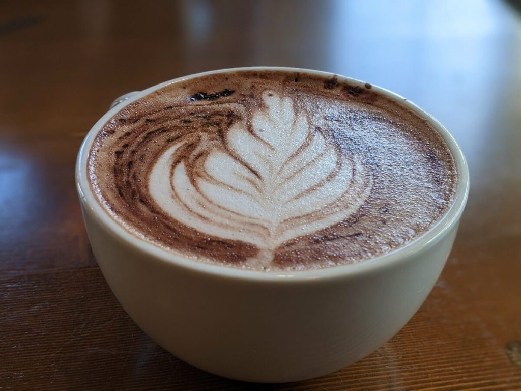 Close up of cup of mocha with coffee art of a leaf in the milk foam at Wayne and Freda