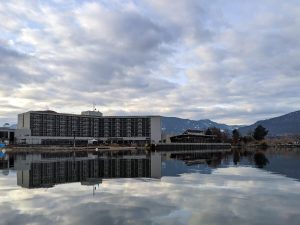 Reflection of Lakeside Resort building and Hooded Merganser Restaurant on calm water surface of Okanagan Lake