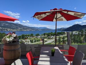 View of six person table at Play Winery Restaurant with umbrella and gorgeous lake views in the background