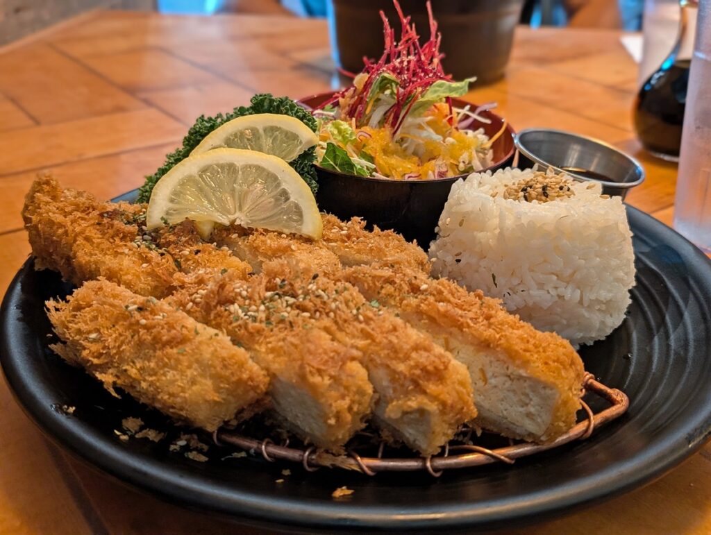 Close up of katsu dish at Katsu Heaven with fried tofu cutlet, with circle of rice and salad