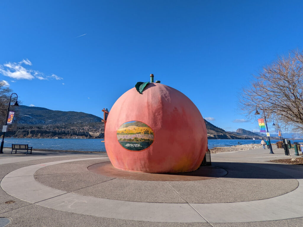 Giant peach kiosk with a painting of Munson mountain on its side.