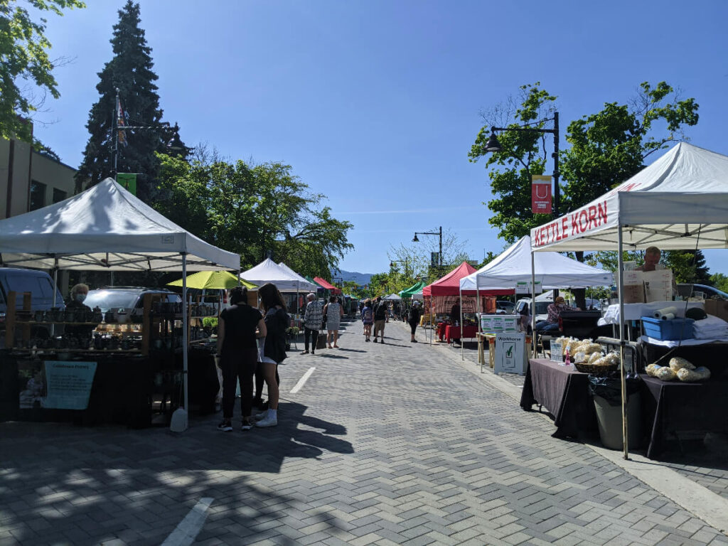 People walking between kiosk at the Penticton farmers market