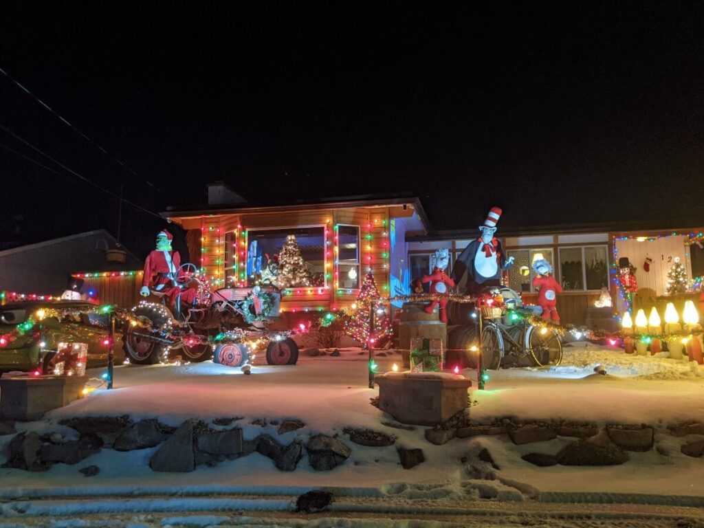 Roadside view of house on Granby Avenue with lighting around fences and building walls, with Grinch characters in the garden