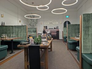 Chronos Tasting Room at Time Winery with long bench in the middle, large booth seating on both sides of the room and Chronos logo in background