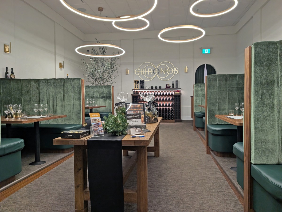 Chronos Tasting Room at Time Winery with long bench in the middle, large booth seating on both sides of the room and Chronos logo in background