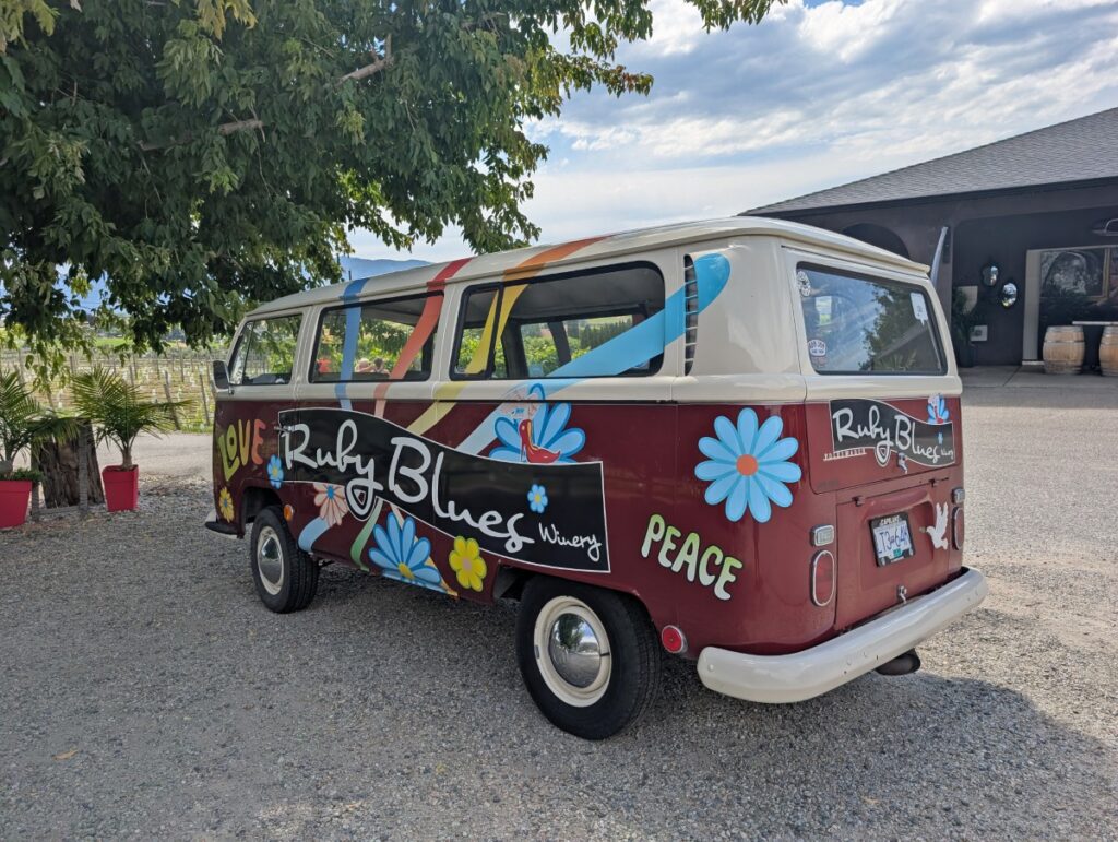 Colourful Ruby Blues Winery VW van decorated with flowers and peace/love text, parked under a tree at the winery