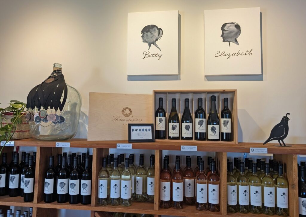 Close up of wine rack displays in Three Sisters tasting room, with side portraits of two of the sisters above