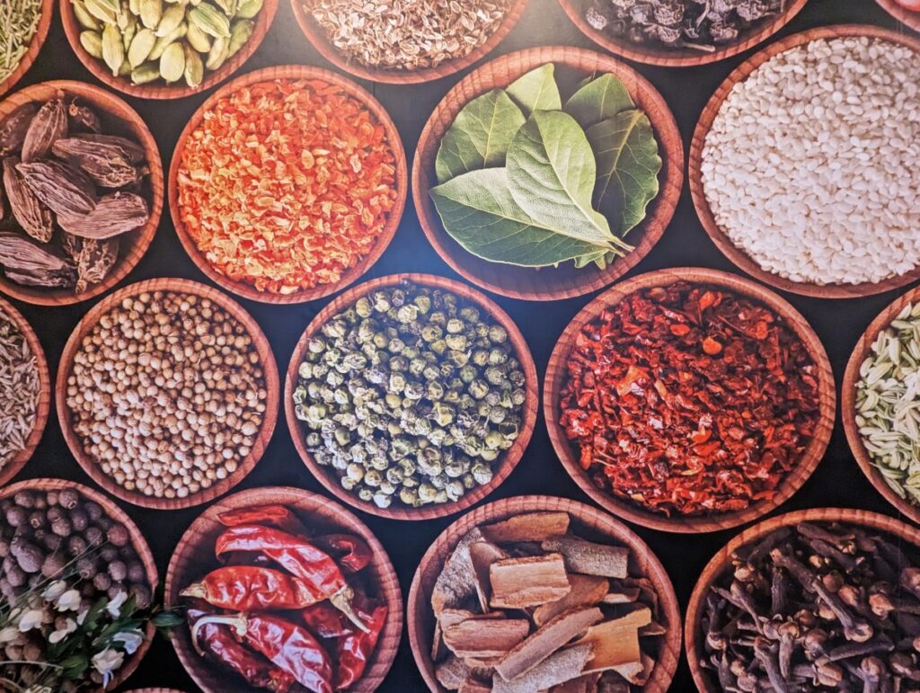Artwork at Lachi Fine Indian Cuisine (one of Penticton's best Indian restaurants) featuring overhead photo of small  dishes filled with whole spices (bay leaves, cinnamon sticks, cloves etc)