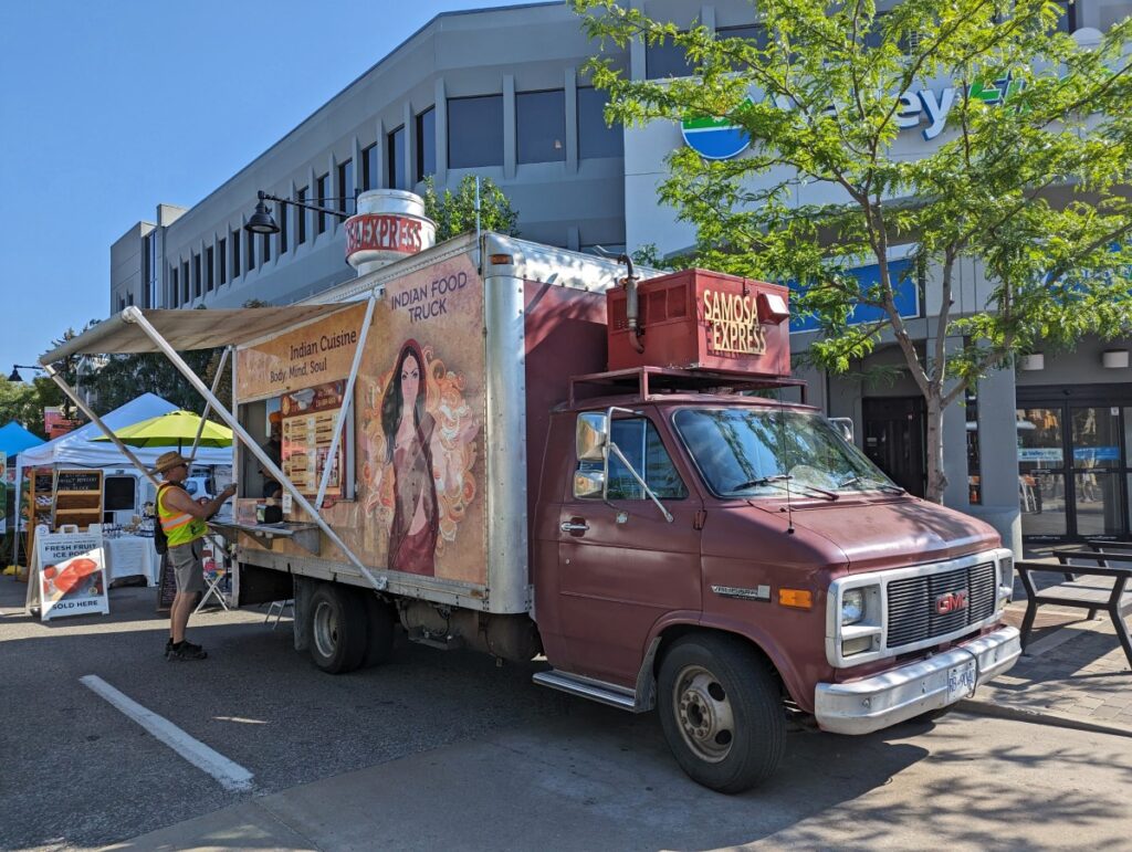 Side view of Samosa Express cube shaped food truck parked at Penticton Farmers Market
