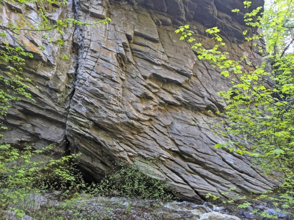 View of layered cliff on Naramata Creek Falls Trail with forest in foreground