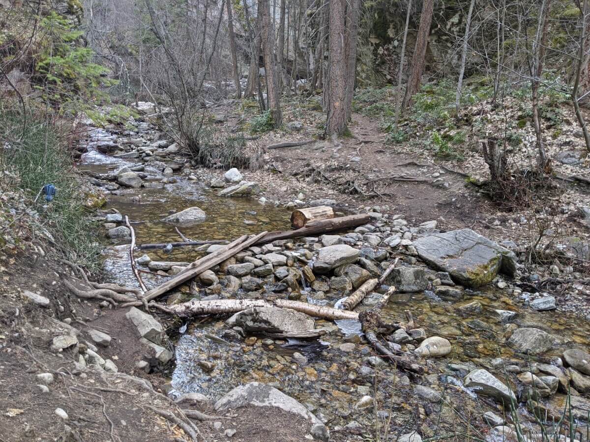 View of Naramata Creek crossing at low water level time, with rocks and logs providing an easy way to cross the creek