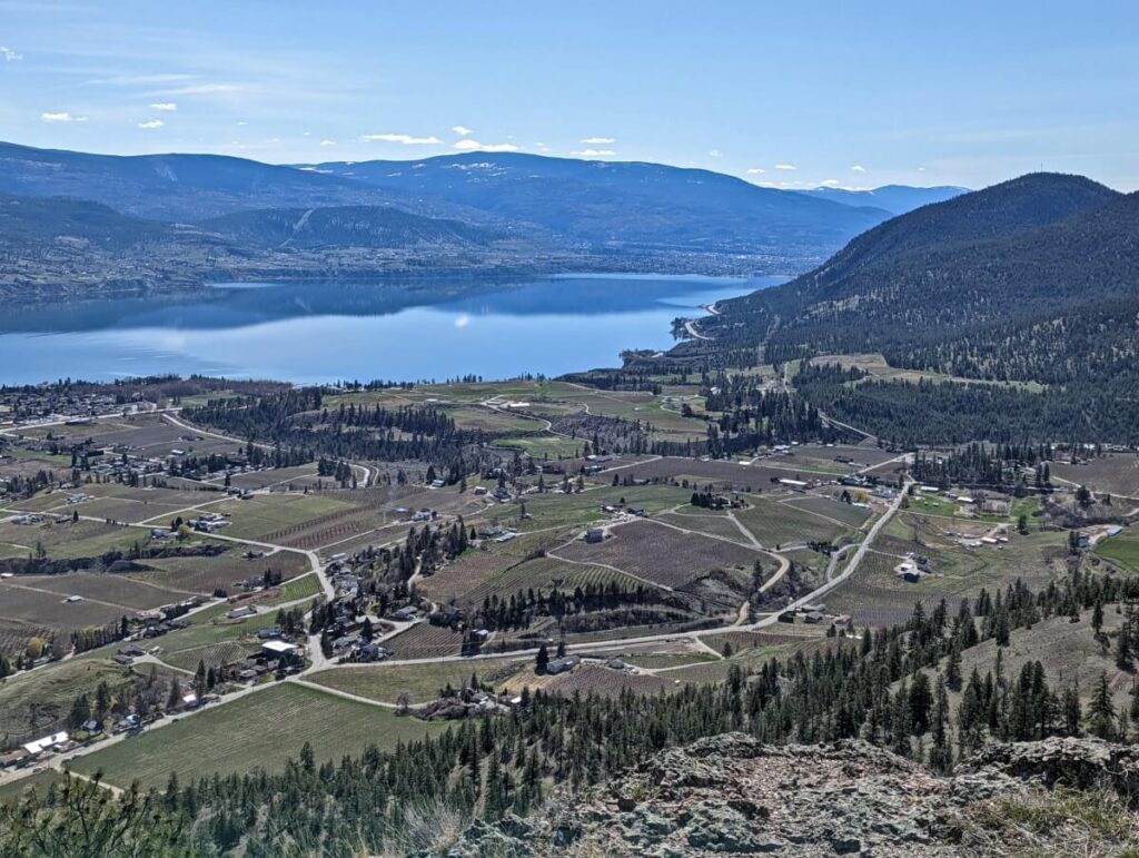 View from top of Giant's Head Mountain summit down to vineyards in Trout Creek area with Okanagan Lake in background