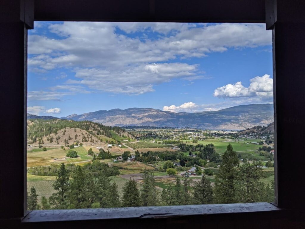 Looking through gazebo window to vineyards in Summerland, with mountains in background
