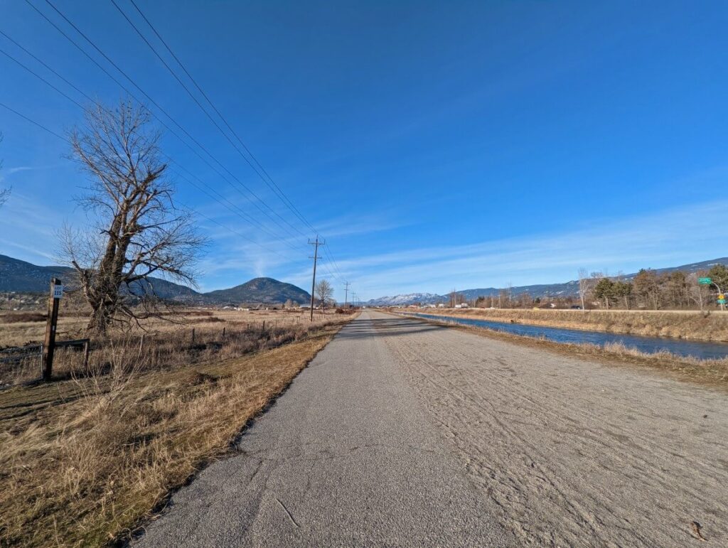 Penticton Channel Pathway with paved and dirt path leading away from camera next to straight waterway