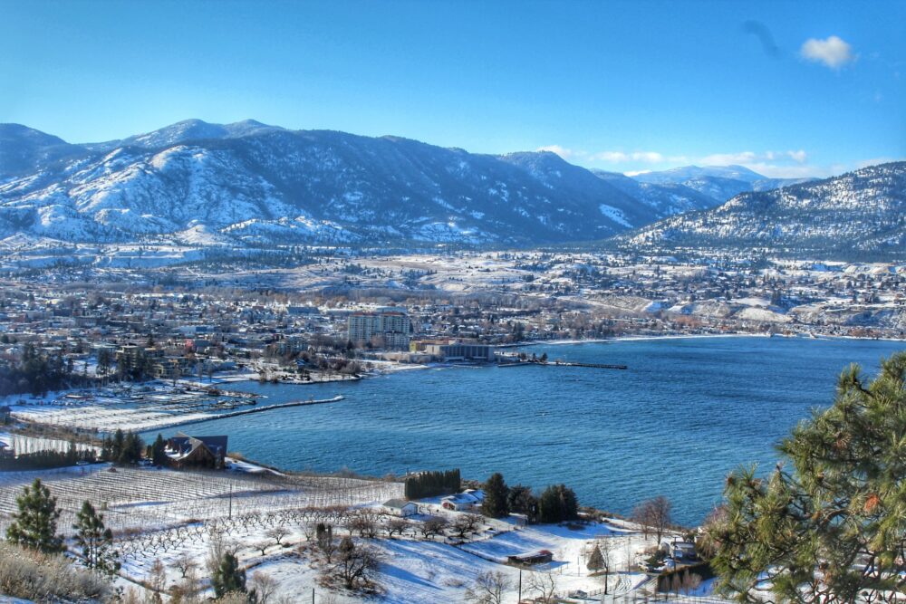 Munson Mountain view of the city of Penticton in winter, with snow on vineyards, marina, surrounding mountains