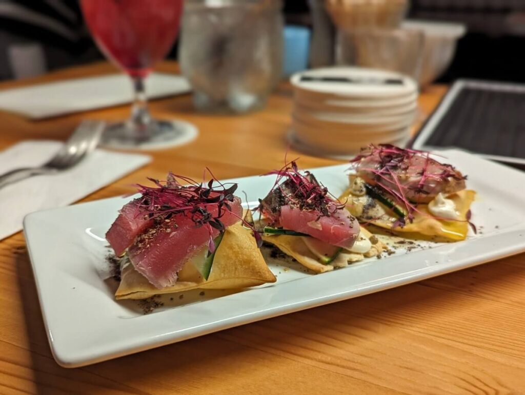 Close up of seared tuna dish at Chulo, featuring three pieces of pink tuna on crackers