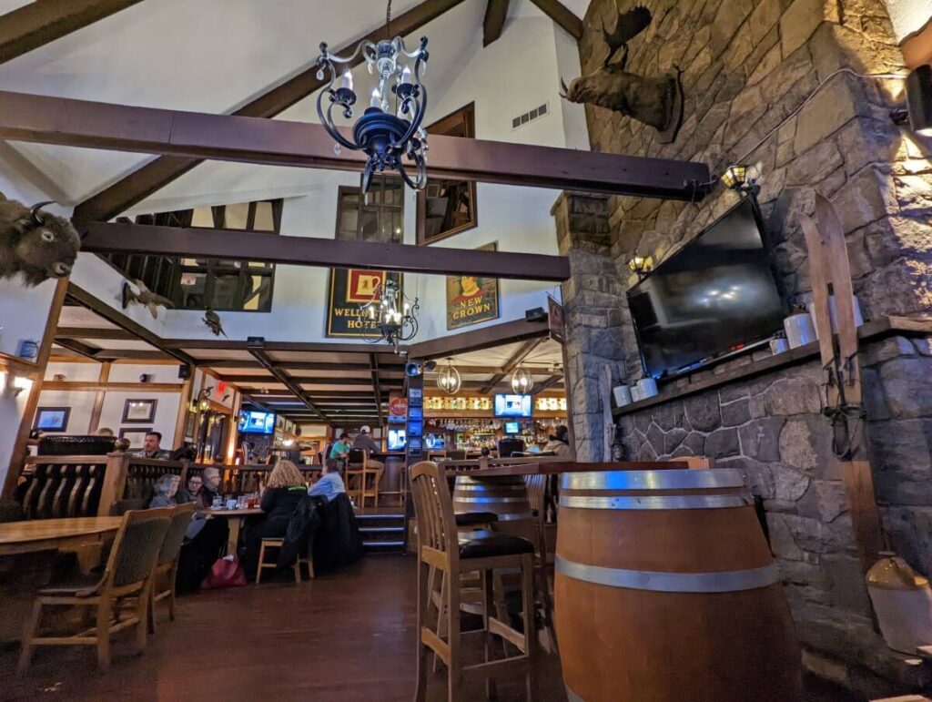 Interior of Barley Mill Brew Pub with low beams, white ceiling, rock fireplace and wooden seating