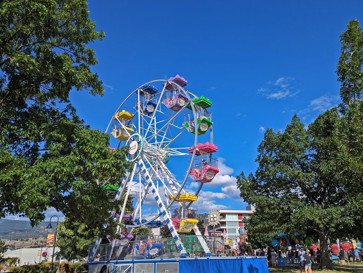 Colourful ferris wheel at Penticton's travelling carnival, situated in a lakeside park during summer