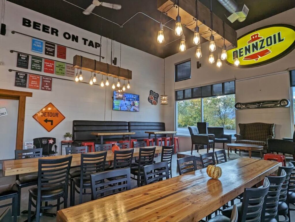 Interior of Highway 97 Brewing with long wooden tables, cosy chairs on raised platform and motor themed signs on walls