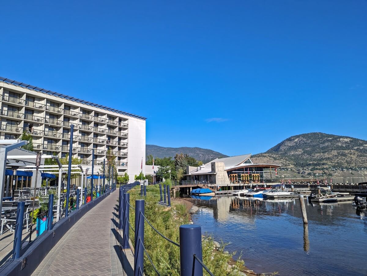 Side view of Penticton Lakeside Resort with Okanagan Lake on the right, a stilted restaurant on the water and a hotel building to the left