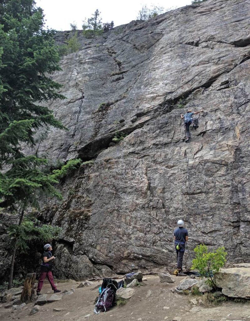 Back view of climbers ascending and belaying at rock climbing wall at Skaha Bluffs in Penticton