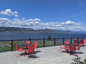Bench 1775 patio view with multiple table and chair sets on large elevated patio, in front of vineyard and Okanagan Lake views