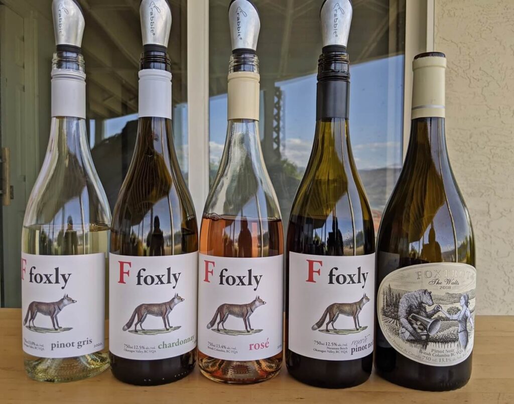 Foxtrot Vineyard tasting lineup, with five bottles of wine on table, with Pinot Gris on the far left, then Chardonnay, Rose and two Pinot Noirs. Four of the five labels are from the Foxly line