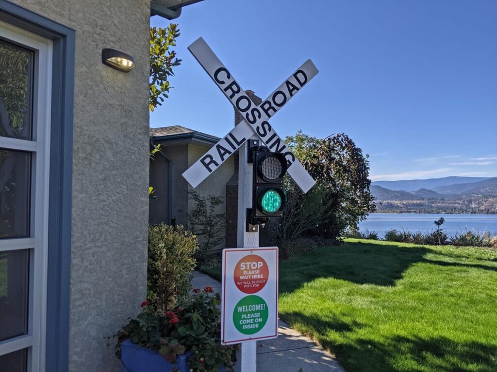 Close up of railroad crossing sign outside Kettle Valley Railway building, with Okanagan Lake views visible on right