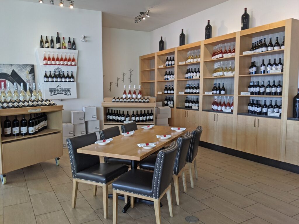 Play Estate Winery interior with six person table (empty) and display cases filled with wine. White clean walls in background
