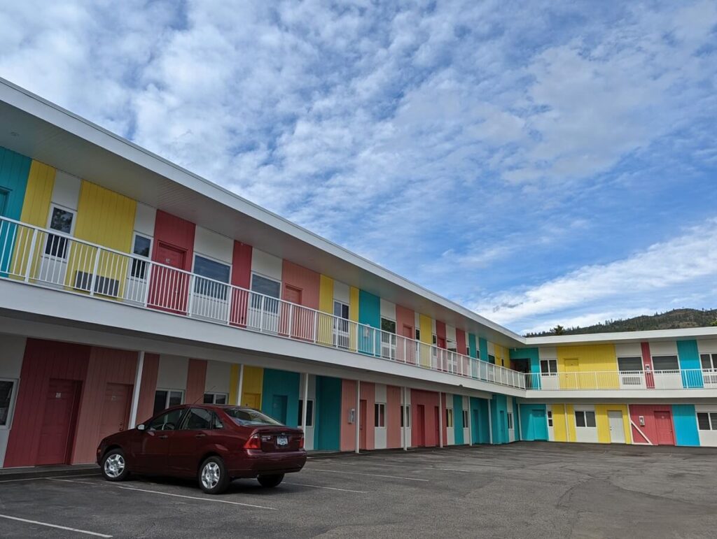 Side view of colourful L shaped  two floor motel building with parked car
