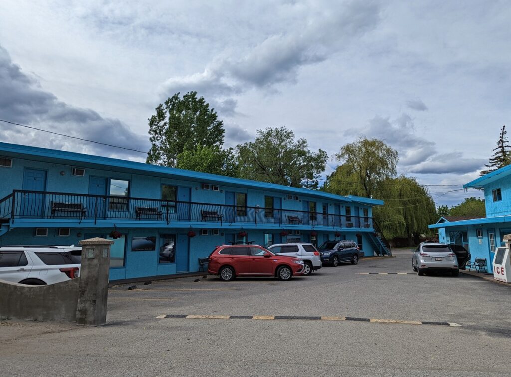 Lakeside Villa Inn and Suites, a two floor blue painted motel style building in front of trees