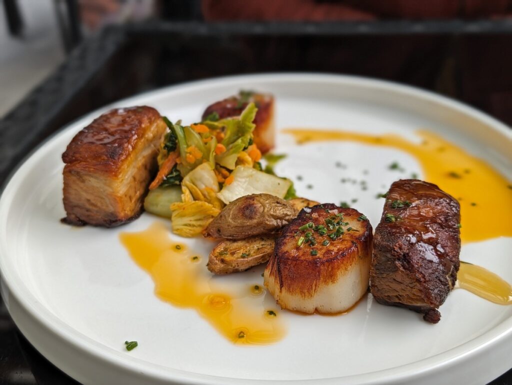 Close up of scallops and pork belly dish at Hillside Winery on white plate