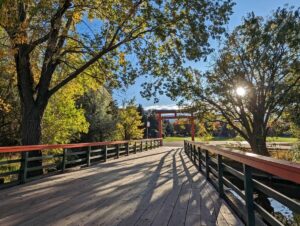 Late afternoon view of Penticton footbridge with Japanese Torii gate on other side, surrounded by trees