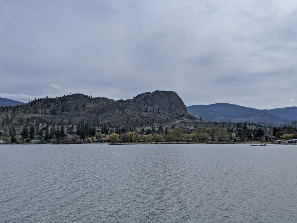 Bridge view of calm Skaha Lake, Okanagan Falls community and Peach Cliff looming above